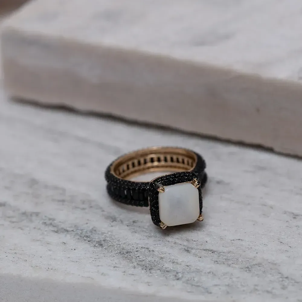 ANEL SOLITÁRIO MADRE PÉROLA CRAVEJADO COM ZIRCÔNIAS NEGRAS BANHO OURO 18K