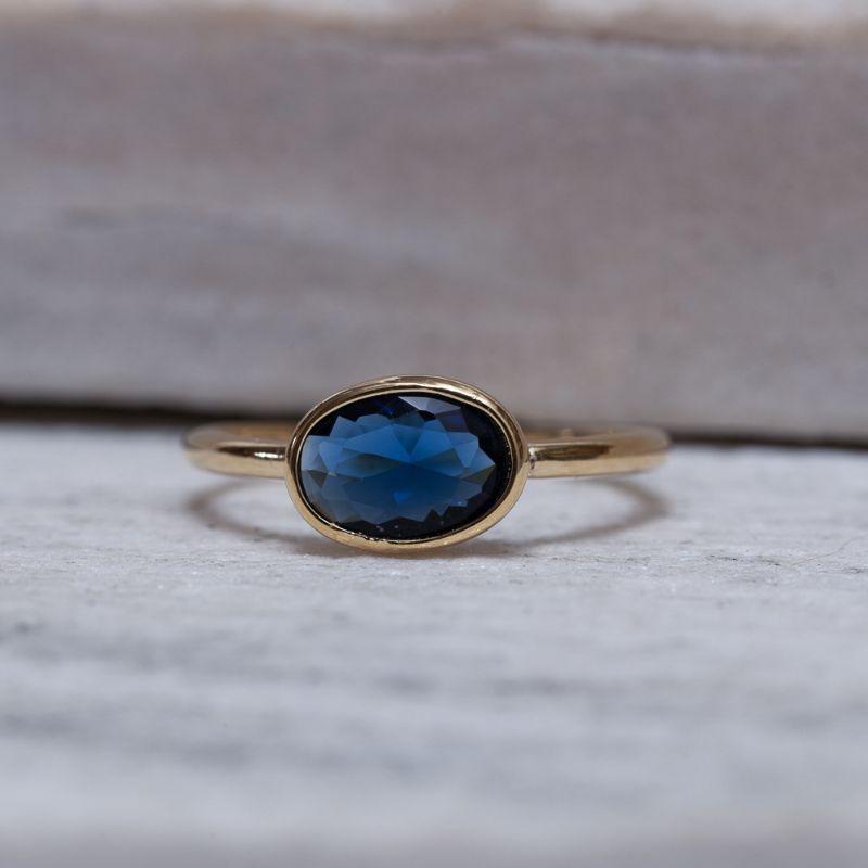 ANEL REGULÁVEL OVAL COM PEDRA AZUL ESCURO BANHO OURO 18K